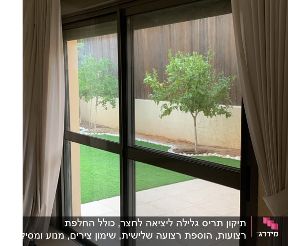 חלון זכוכית עם וילונות וגינה בחוץ